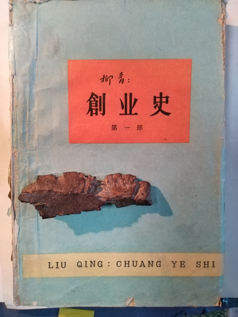 長篇小說《創(chuàng)業(yè)史》（第一部）書影與柳青曾收藏的彈片。 （文金 攝）